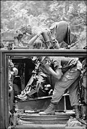 Schwarz-Weiß-Foto eines Soldaten, der ein Artilleriegeschütz aus einem Kettenfahrzeug abfeuert