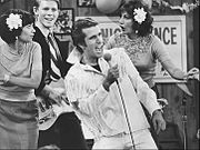 The Fonz becomes a singing superstar. Pictured are Cindy Williams as Shirley Feeney, Ron Howard as Richie Cunningham, Henry Winkler as Fonzie, and Penny Marshall as Laverne DiFazio. Happy Days Fonzie Superstar 1976.JPG