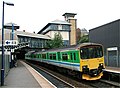 A Worcester-bound train on platform 1, far below street level which is on the level of the top floor of the building behind.