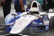 Zdjęcie Wilsona siedzącego w swoim niebiesko-białym samochodzie wyścigowym w boksie na wyścigu Indianapolis 500 . 2015