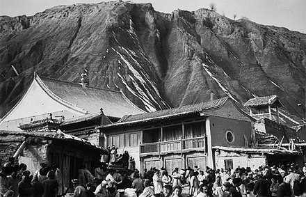 Muslims at the mosque with a minaret and market, Dongxiang County, Gansu, 1934.