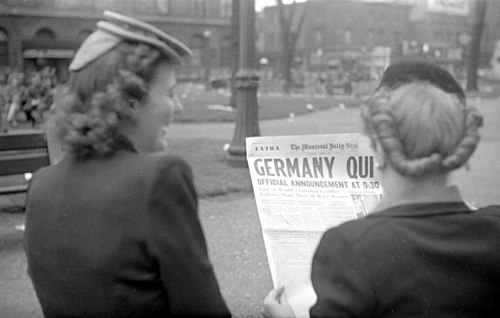 Deux jeunes femmes lisant la une du Montreal Daily Star annonçant la capitulation allemande et la fin imminente de la Deuxième Guerre mondiale, 7 mai 1945