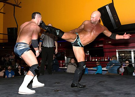 Pepper Parks performing a superkick on Tyson Dux