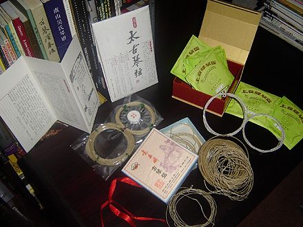 A selection of different qin strings. Top to bottom: (太古琴絃) Taigu Silk Qin Strings (中清 zhongqing gauge) with a container of 'string gum' (絃膠), (上音牌琴弦) Shangyin Shanghai Conservatorie Quality Qin Strings (metal-nylon), (虎丘古琴絃) Huqiu Silk Strings