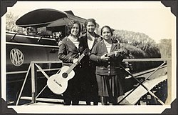 Three young women with a guitar and a ukelele, stand in front of a Hawaii Consolidated Railway steamtrain, Hilo Region, Hawaii, 1929 - C.M. Yonge (16216486554).jpg