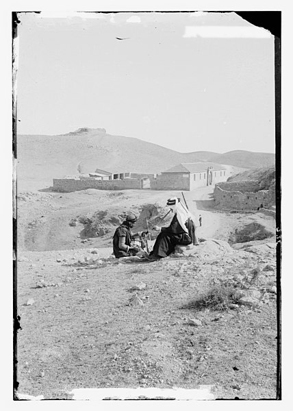 File:Two men seated in front of building, one with rababeh (a single string instrument) and the other with a pipe LOC matpc.11712.jpg