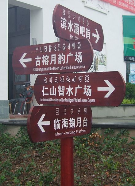 A signpost in a public park in Xichang, Sichuan, China, showing Modern Yi, Chinese and English text.