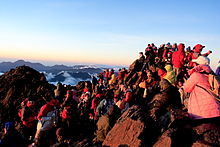 Vue du sommet avec des centaines de randonneurs profitant du lever de soleil.