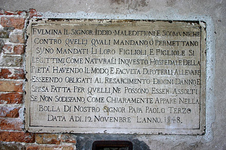 Plaque where once stood the ruota ("the wheel"), the place to abandon children at the side of the Chiesa della Pietà, the church of an orphanage in Venice. The plaque cites on a Papal bull by Paul III dated 12 November 1548, threatens "excommunication and maledictions" for all those who – having the means to rear a child – choose to abandon him/her instead. Such ex-communication may not be canceled until the culprit refunds all freights incurred to raise the baby.