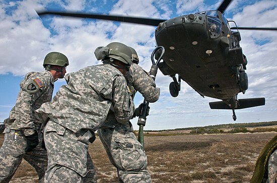 Students brace against the rotor-wash of a UH-60 Black Hawk as they prepare to attach a slingload during one of the practical exercises.