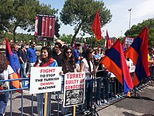 Photographie de manifestants portant des drapeaux arméniens et des pancartes en anglais accusant la Turquie de déni.