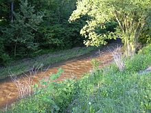 Rot gefärbtes Sediment, das in der schwebenden Ladung mitgeführt wird, die sich in einem Schwemmkanal bewegt