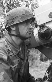 German paratrooper looks through the reflector sight of the Flakvisier 40 gunsight on a FlaK 38 anti-aircraft gun (1944), one of the more sophisticated sights at the time Bundesarchiv Bild 101I-584-2165-12, Frankreich, Fallschirmjager an Geschutz.jpg