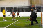 Grand Rapids Dragonfish shooter (black and orange) and Detroit Coney Dogs defender (yellow) look on as Coney Dogs goalie (black) traps ball