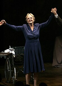 An elderly woman with her arms held aloft