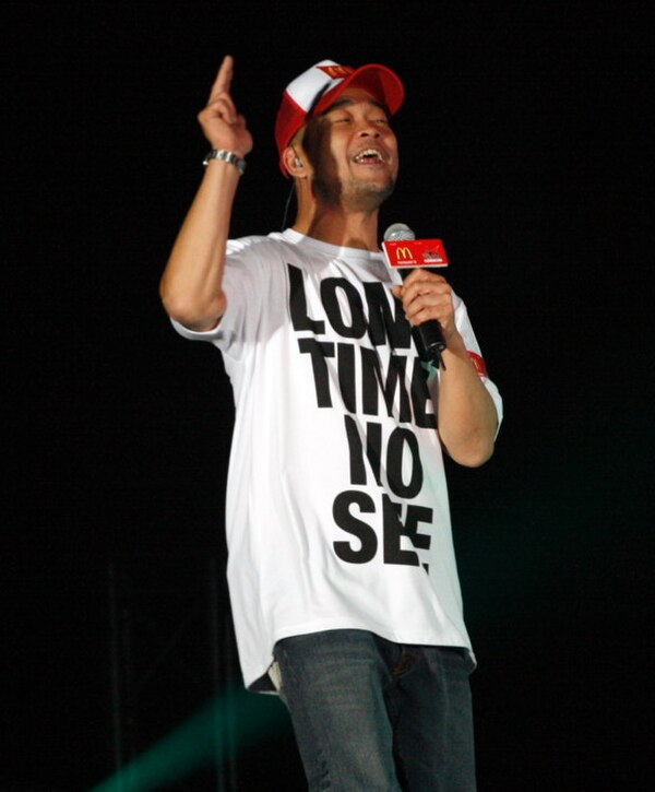 Eric Kot wearing a "Long Time No See" concert commemorating T-shirt at a public event.