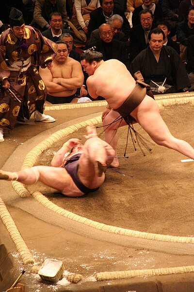 A makuuchi match with the 69th yokozuna Hakuhō beating Dejima as the 68th yokozuna Asashōryū watches in the background