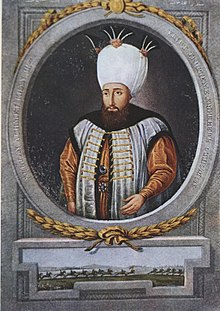 Image montrant un homme en costume d'apparat portant barbe et moustache et un haut turban blanc