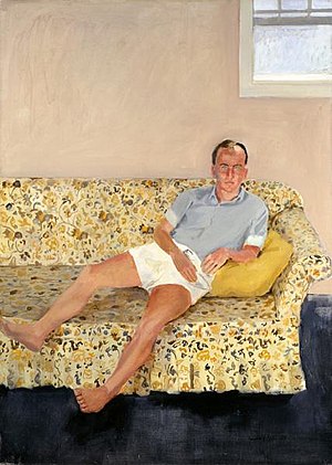 Image of man on a sofa in white shorts and gray shirt leaning on a yellow pillow