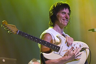 A man wearing a sleeveless white shirt holding a white guitar