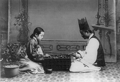 A Korean couple playing Go in traditional dress. Photographed between 1910 and 1920.