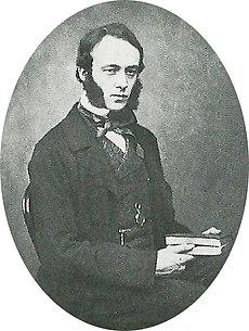 A young man with dark hair and huge sideburns