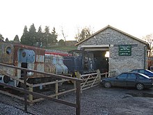 Bâtiment en pierre avec locomotive à vapeur à l'extérieur.