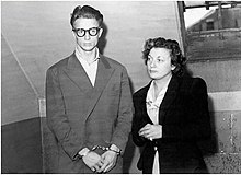 Black and white photograph of a handcuffed man with a woman at his side.