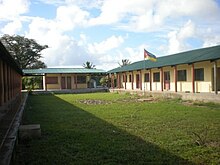 Klassenzimmer sowie der Cantina- und Zubehörladen der Schule (am Ende des Blocks).