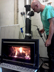 Technician using ASTM Smoke Spot Pump to evaluate emissions from an experimental wood stove Stove Test.jpg