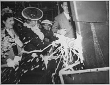 Woman smashing a bottle on the bow of a ship