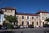 Vue d'un bâtiment en pierre de taille et meulière, pavillon central à 1 étage ; ailes à 2 étages.