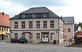 Wohn- und Geschäftshaus (heute Sparkasse, ehemals Gasthaus „Zum Löwen“) mit Saalanbau, Hintergebäuden sowie Stützmauer mit Einfriedung