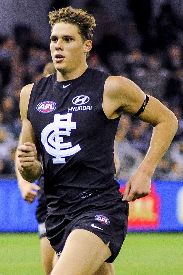 Male athlete in sleeveless guernsey runs during a football match