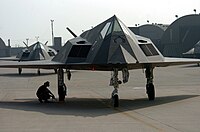 An airman prepares to pull the landing gear wheel chock of an F-117 Nighthawk attack aircraft during an end of runway check at Kunsan Air Base, South Korea.