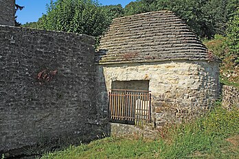 Bâtiment à abside ronde et toit de lave abritant la fontaine.