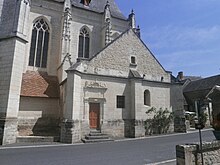 Gedeeltelijk buitenaanzicht van de apsis van een kerk en een aangrenzend gebouw.