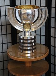 Photographie d'un trophée argenté en forme de coupe.
