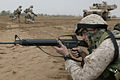 A Marine with an M16A2 on a training exercise at Camp Baharia, Iraq, 2004. An M1 Abrams tank is in the background
