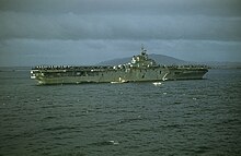 A color photo of an aircraft carrier at sea from a distance