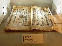 Livre ouvert dans un présentoir de musée. Les pages présentent un texte rédigé en caractères chinois et coréens.