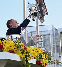 Chad Brown holding the Woodlawn Vase replica trophy, with the original Woodlawn Vase partially visible 147th Preakness Stakes (52093732404).jpg