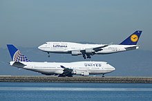 Un Boeing 747-400 de United Airlines rodando mientras un Boeing 747-400 de Lufthansa aterriza.