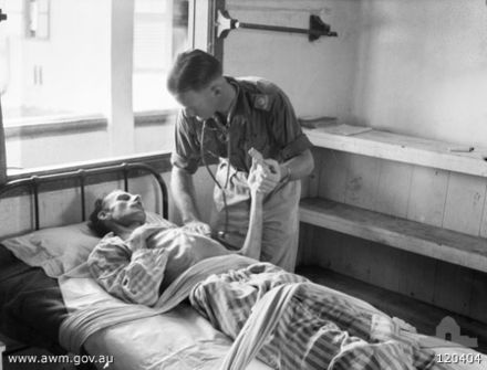 Captain Anderson, a severely emaciated British officer, in Kuching Civil Hospital five days after his liberation from Batu Lintang camp. With him is Major A. M. Hutson, an Australian medical officer.