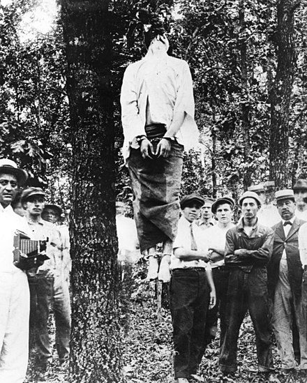 Leo Frank's lynching on the morning of August 17, 1915. Judge Morris, who organized the crowd after the lynching, is on the far right in a straw hat.[207][n 31]