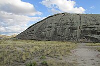 Grande roccia arrotondata che si erge sopra la pianura