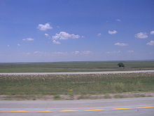 Two roads spanning a flat, grassy plain