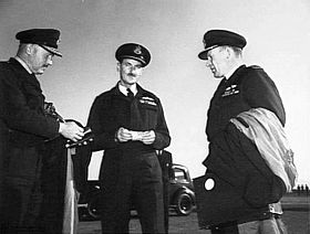 Informal portrait of three men in dark military uniforms with peaked caps
