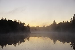 Kinwamakwad Lake (Danau Panjang) di pagi hari. Matahari terbit tetapi belum terlihat dan lapisan tipis dari kabut uap meletakkan di atas permukaan air.