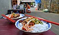 'Bún thịt nướng' contains fresh cold rice vermicelli, raw vegetables with a sour sweet dressing, pickled vegetables, ground red chillies and sweet grilled pork